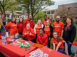 Montclair Alumni gathered around a table wearing matching red "One Day for Montclair" t-shirts