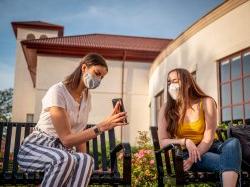 Student showing another student their phone, outside.